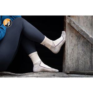 Paar helle Wandersocken mit geripptem Bund und UP-Logo am Knöchel.